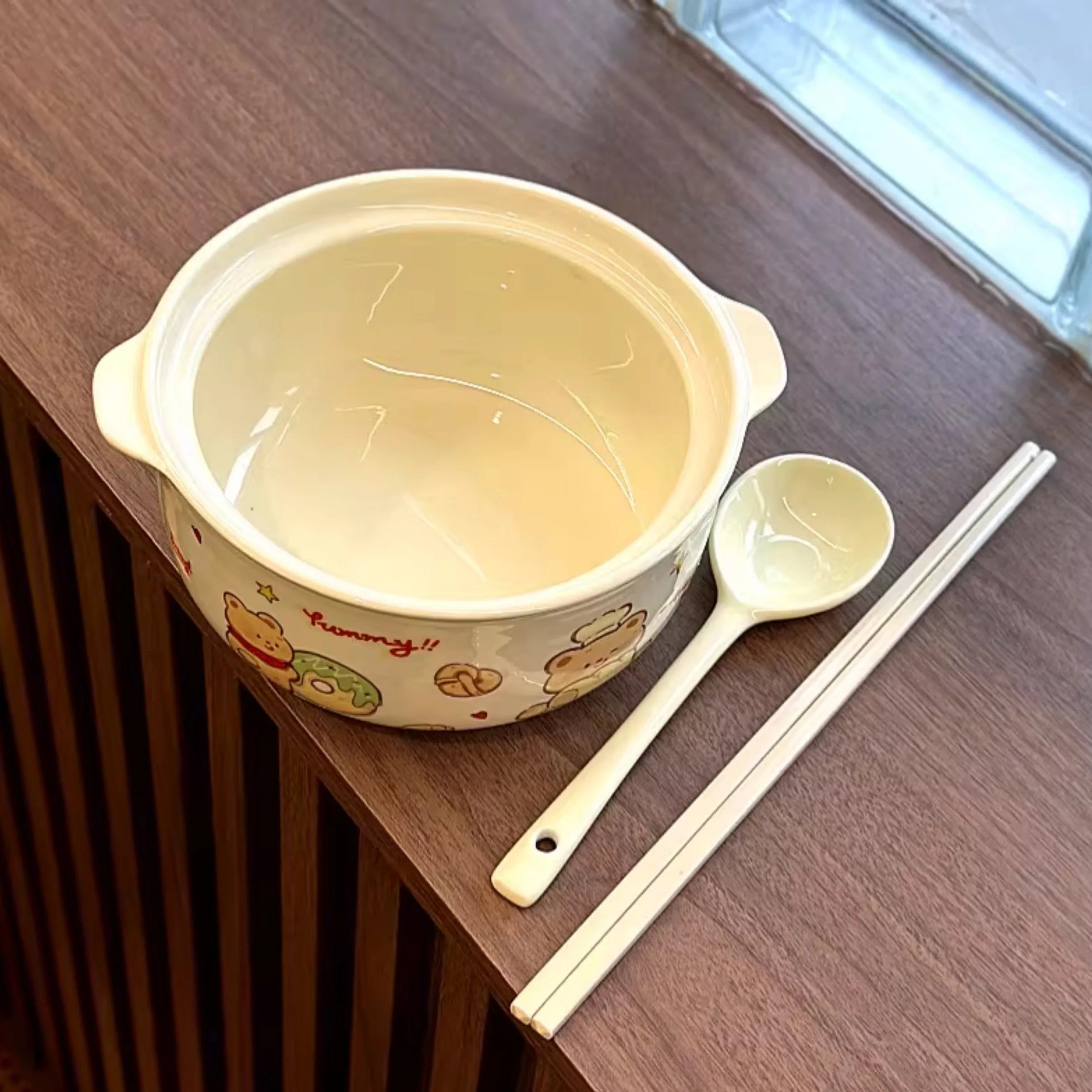 A large cartoon bear kawaii ramen bowl next to spoons and chopsticks