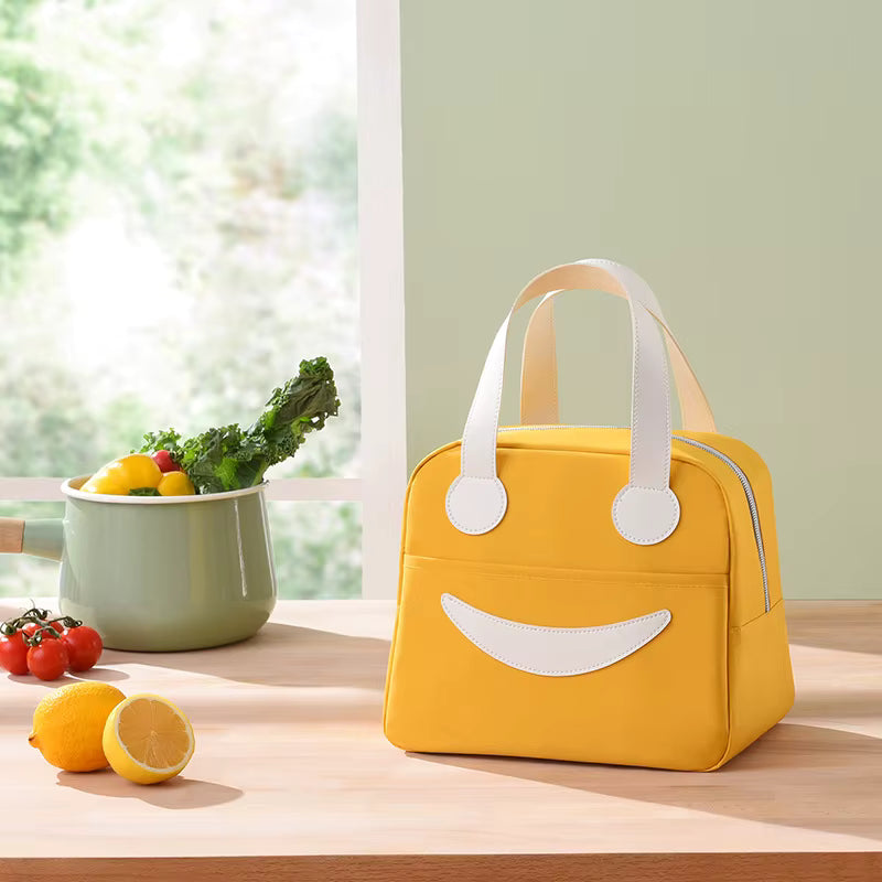 Yellow lunch bag with smiley face design on a wooden table with fruits and vegetables.