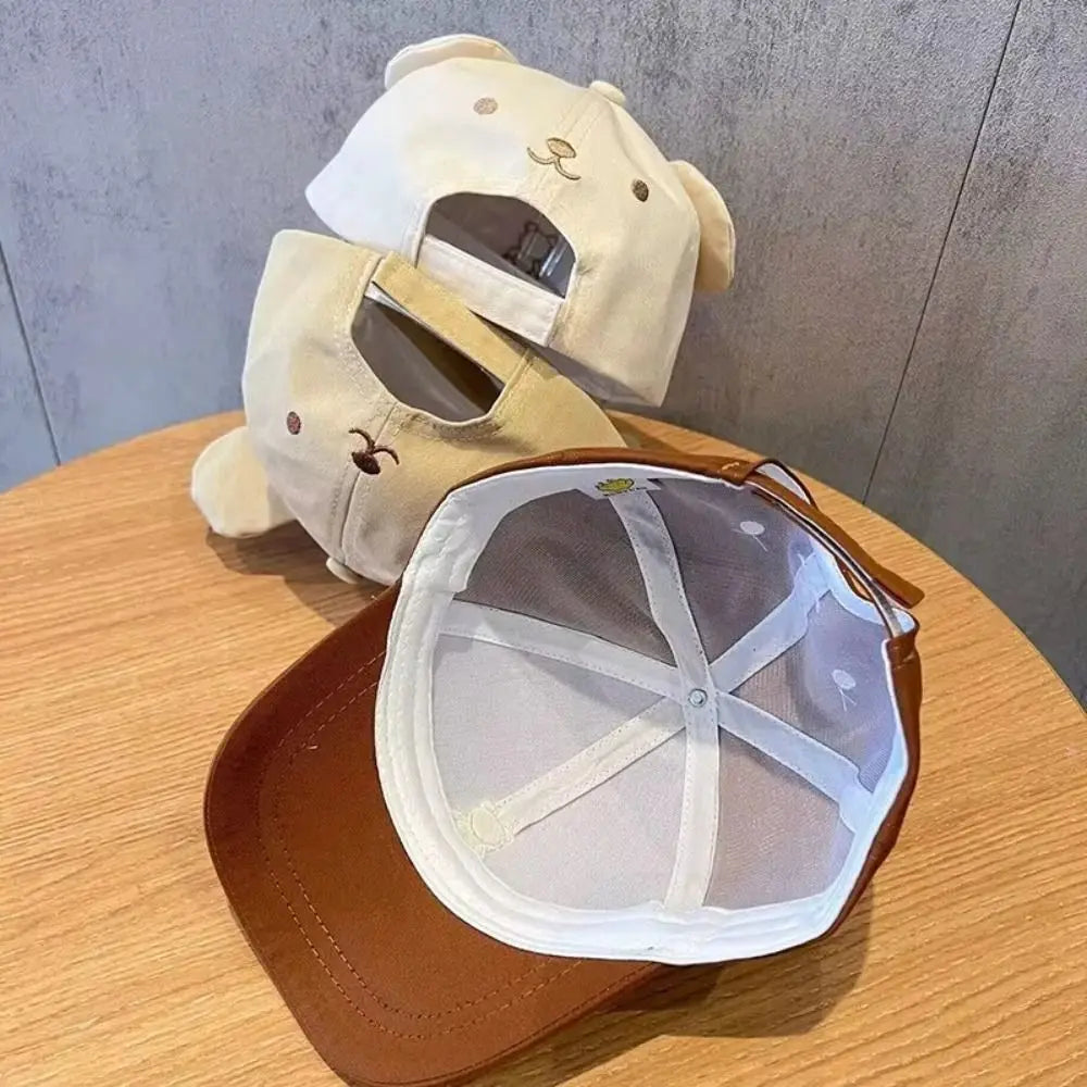 Two Kawaii hats with mesh backs on a wooden surface against a gray wall.