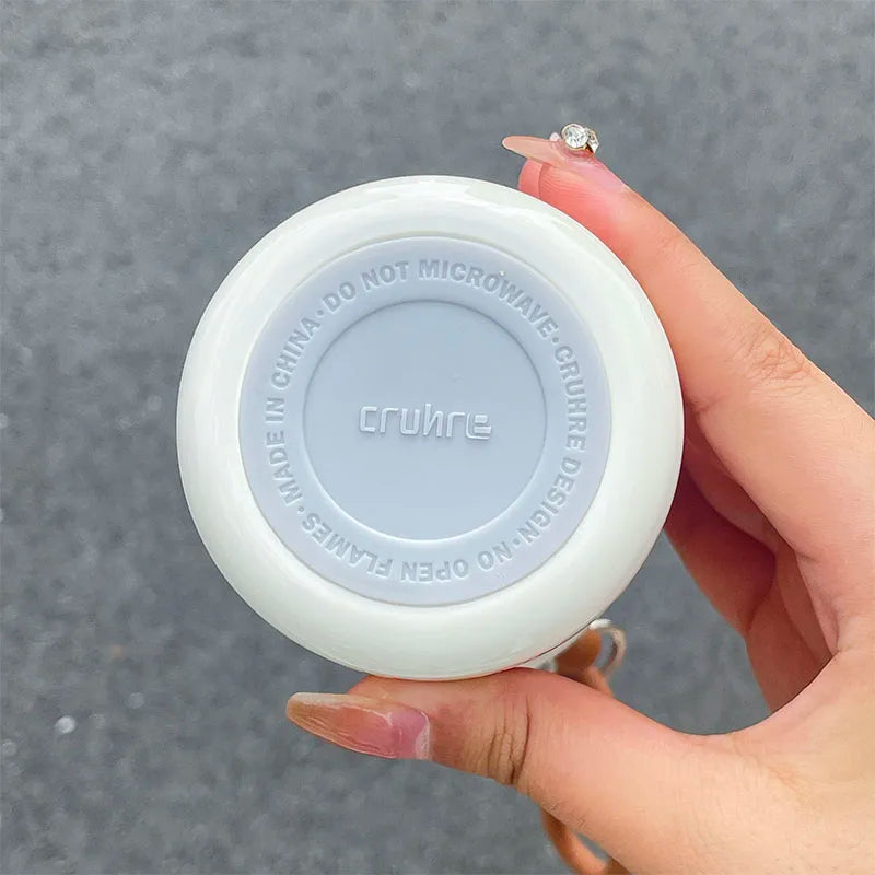 Hand holding a white and gray kawaii water bottle with 'crumpe' branding against a gray background