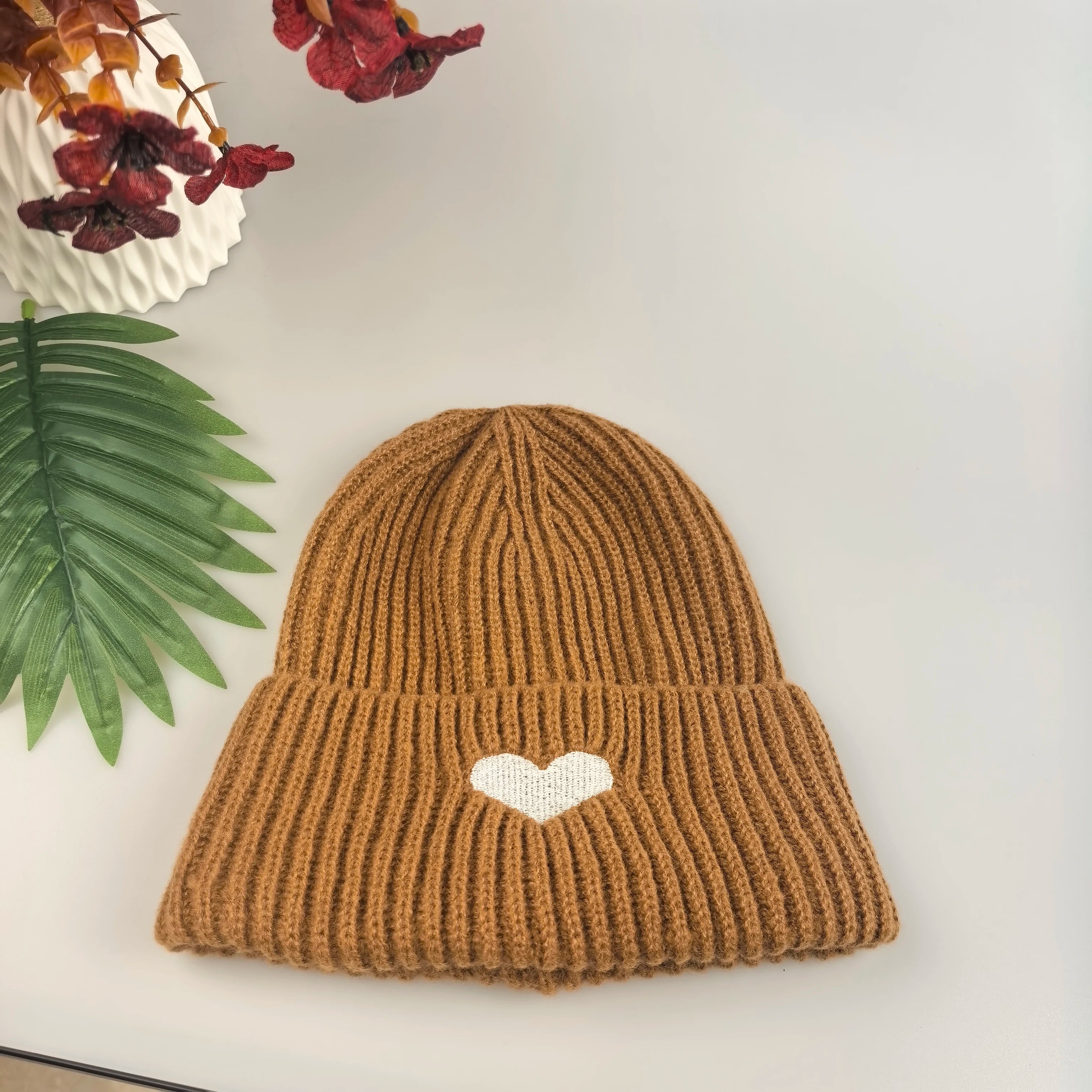Brown knit Kawaii beanie with a white heart on a light background