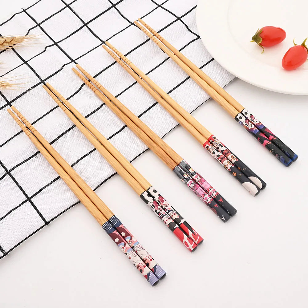 Set of wooden kawaii chopsticks with decorative handles on a checkered tablecloth.