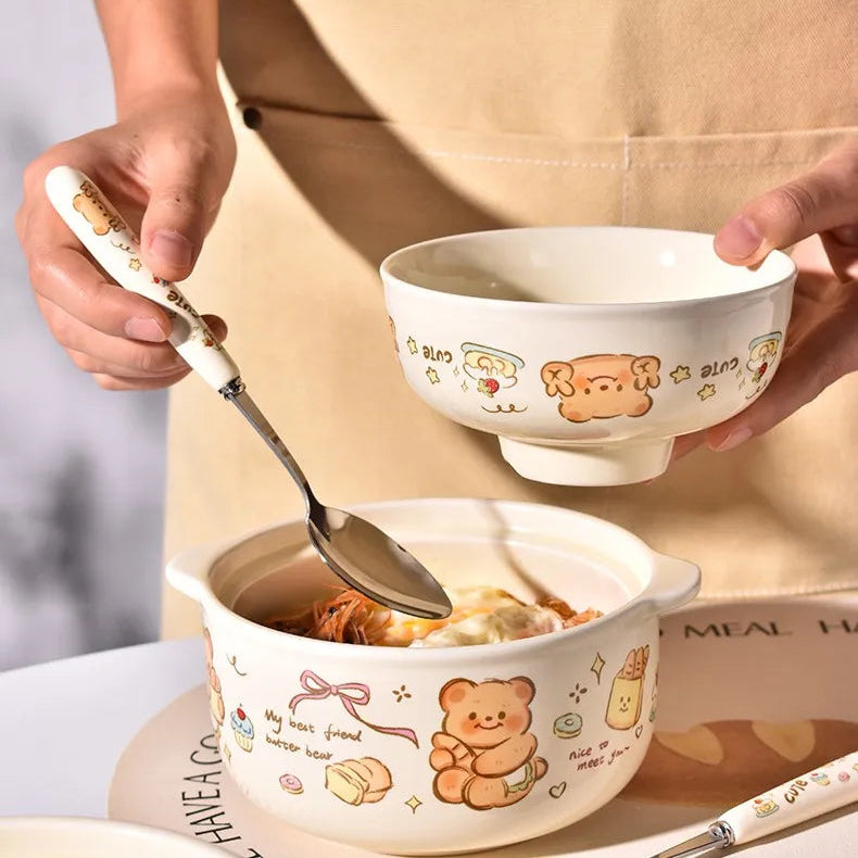 Two cartoon-themed ceramic kawaii ramen bowl with a spoon, held by a person wearing an apron.