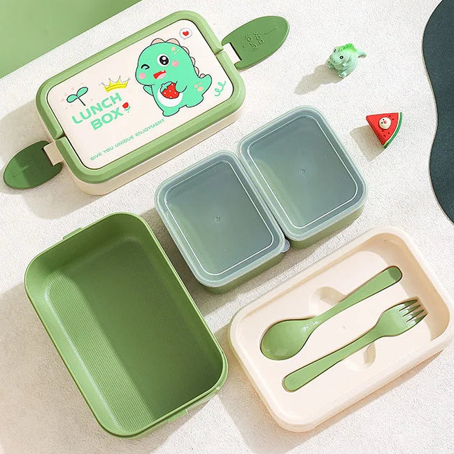 Green children's kawaii lunch box set with compartments and cutlery on a light surface