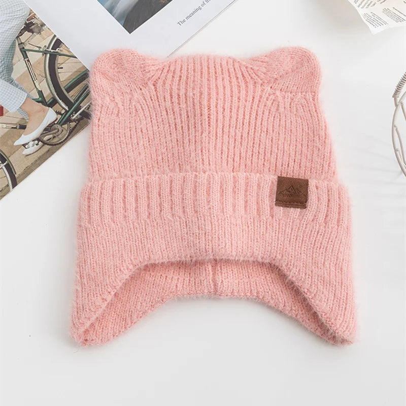 Pink knitted Kawaii beanie with a brand label on a white surface