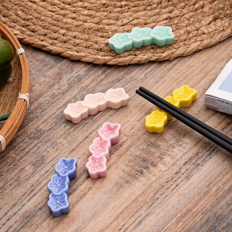 Colorful ceramic kawaii chopstick holders on a wooden surface with a woven mat in the background.