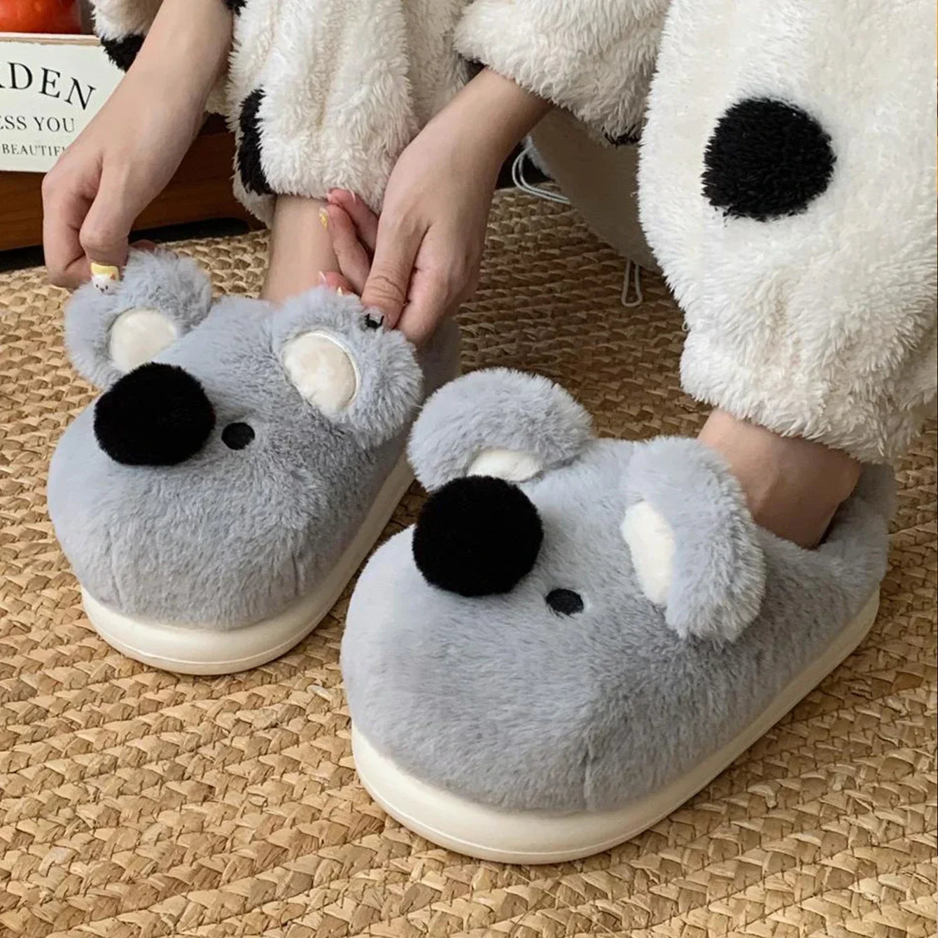 Gray koala kawaii slippers worn by a person on a woven surface