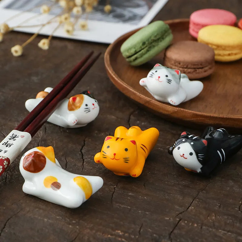 Kawaii cat-shaped ceramic chopstick rest with colorful macarons on a wooden surface