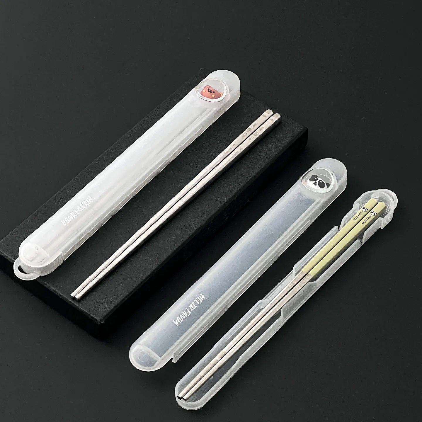 Set of reusable kawaii chopsticks in clear cases on a black background