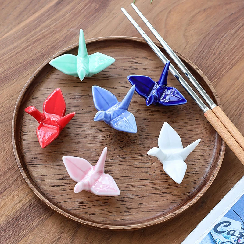 Colorful origami butterfly kawaii chopstick holders on a wooden plate with chopsticks.