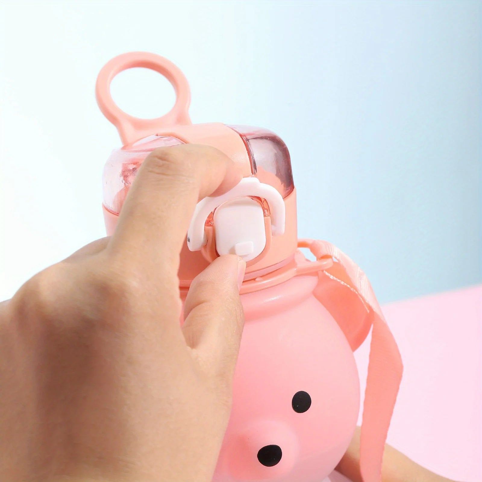 Pink cartoon character kawaii water bottle with a hand holding it against a light blue background