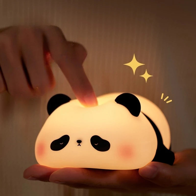 Panda-shaped kawaii night light being held with a hand pressing a button, glowing warmly.