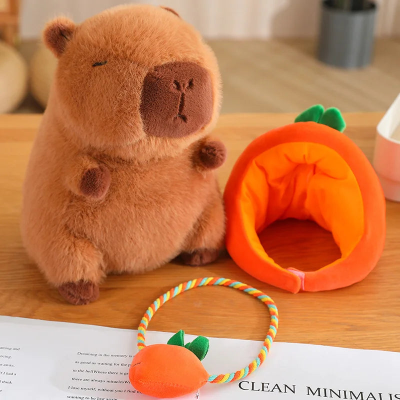 Kawaii plush bear toy and orange pet bed on a wooden surface with a book underneath.