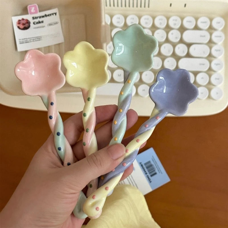 A person holding four rainbow colored kawaii spoons