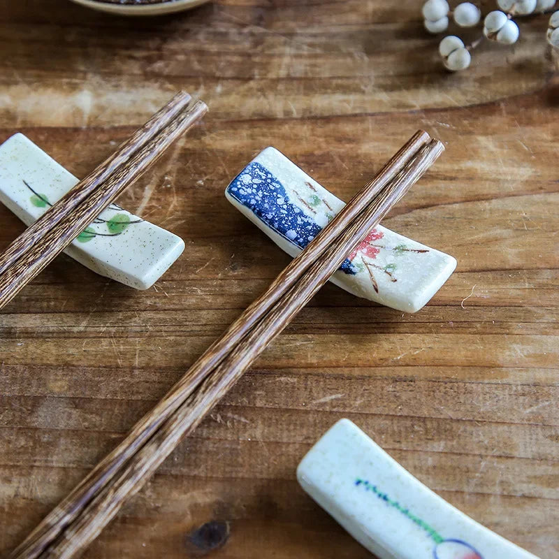 Chopsticks on decorative kawaii chopstick holders with floral patterns on a wooden surface.