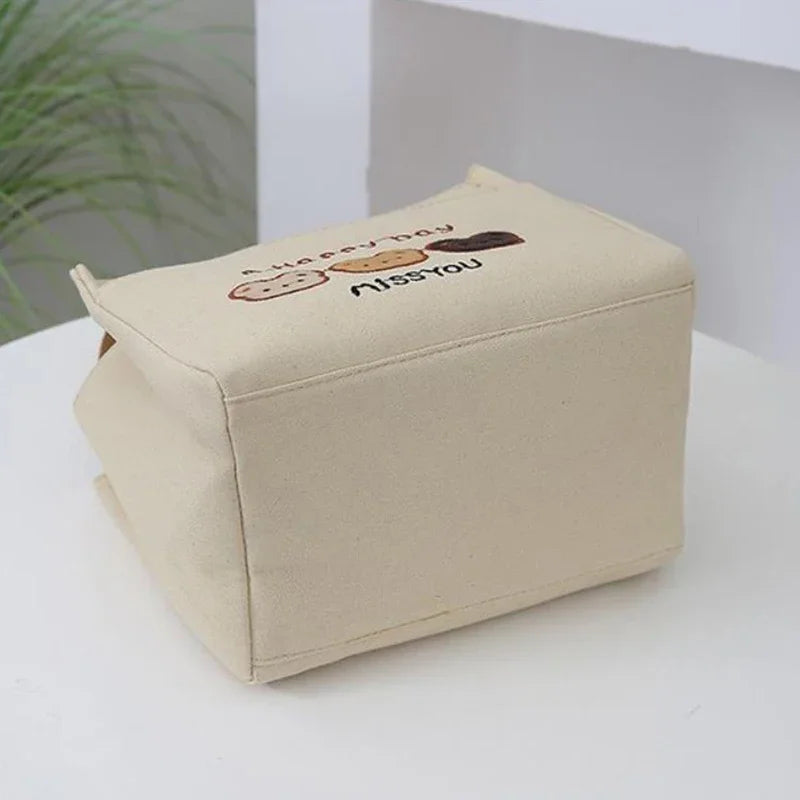 Beige rectangular kawaii bag with embroidered text and design on a white surface.