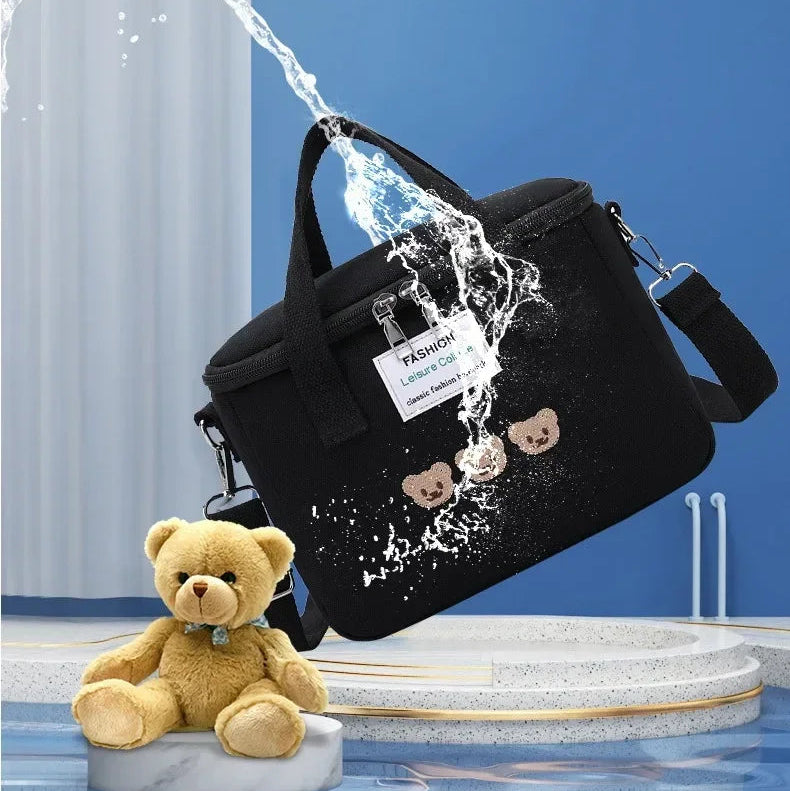Black kawaii bag with teddy bear design being splashed by water, with text about waterproof fabric.