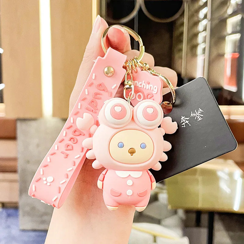 Pink kawaii cartoon character keychain with a strap held by a hand in an indoor setting.