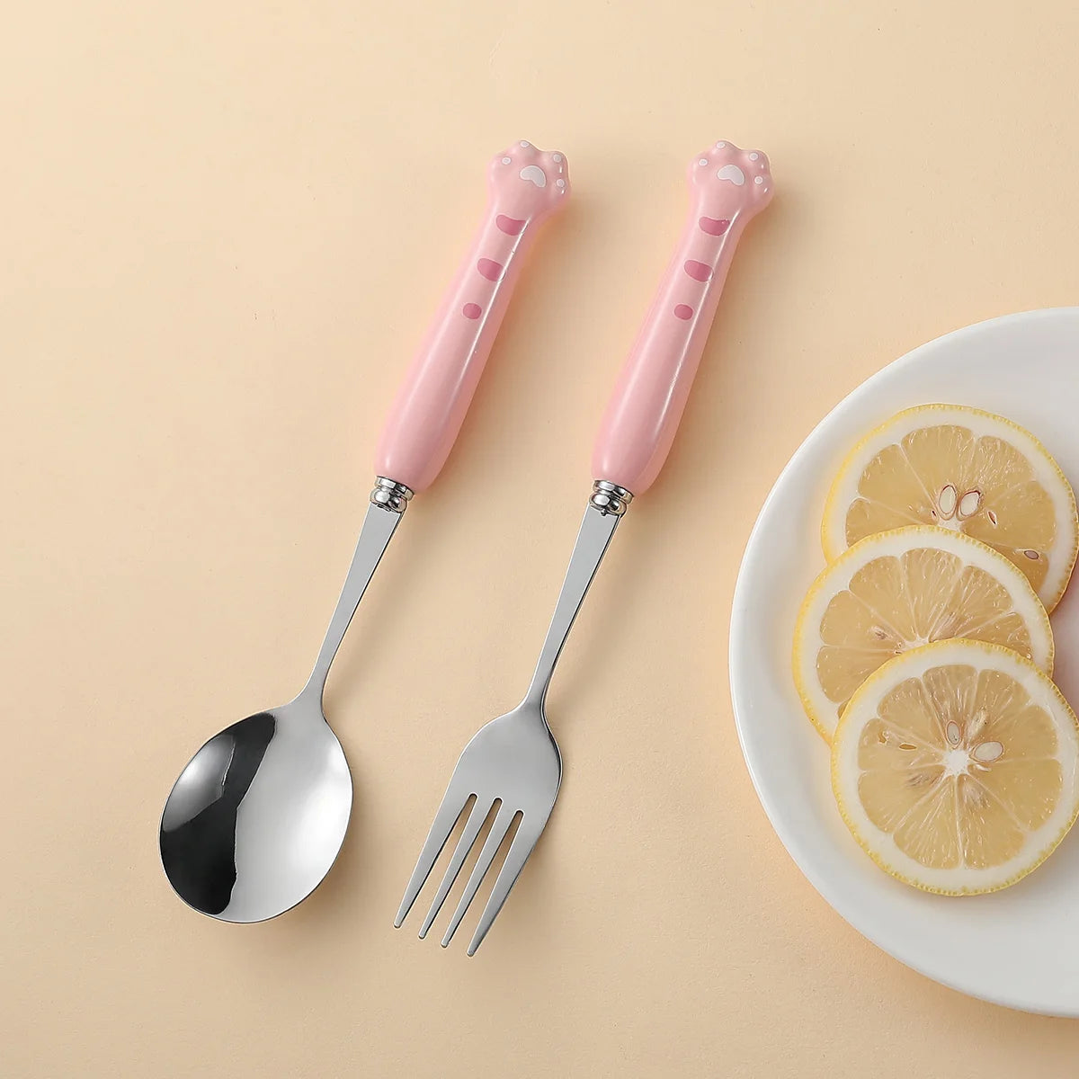 A set of pink, paw shaped kawaii utensils on a yellow background