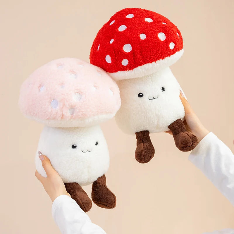 Two kawaii plush mushroom toys with red and pink caps held by a person against a beige background