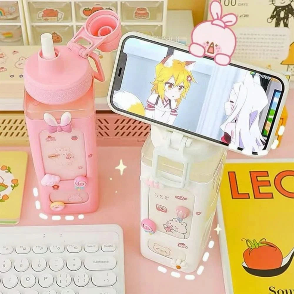 Pink kawaii water bottle with bunny design, phone stand, and smartphone displaying anime character on a desk.