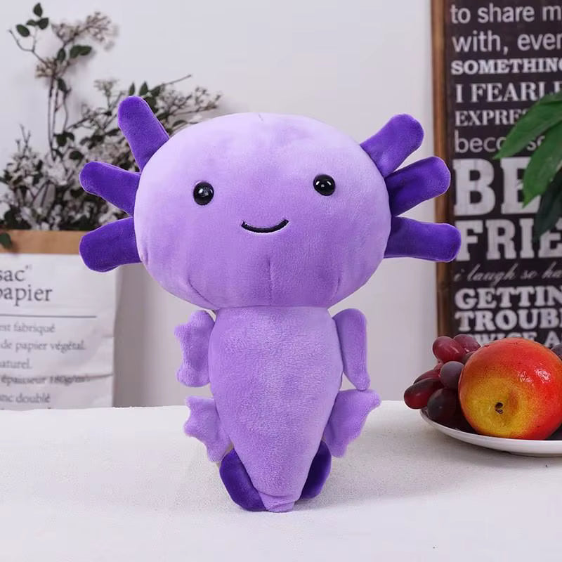 Purple plush toy with a smiling face on a white surface with fruits and a plant in the background.