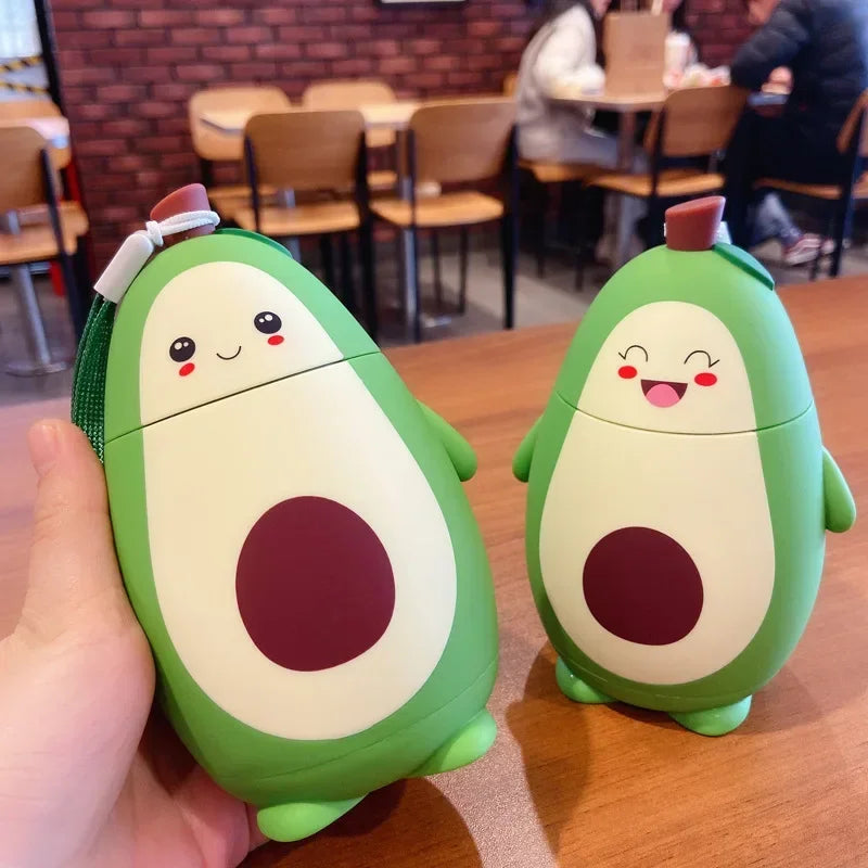 Two avocado-shaped kawaii water bottles with cartoon faces on a table in a casual setting.
