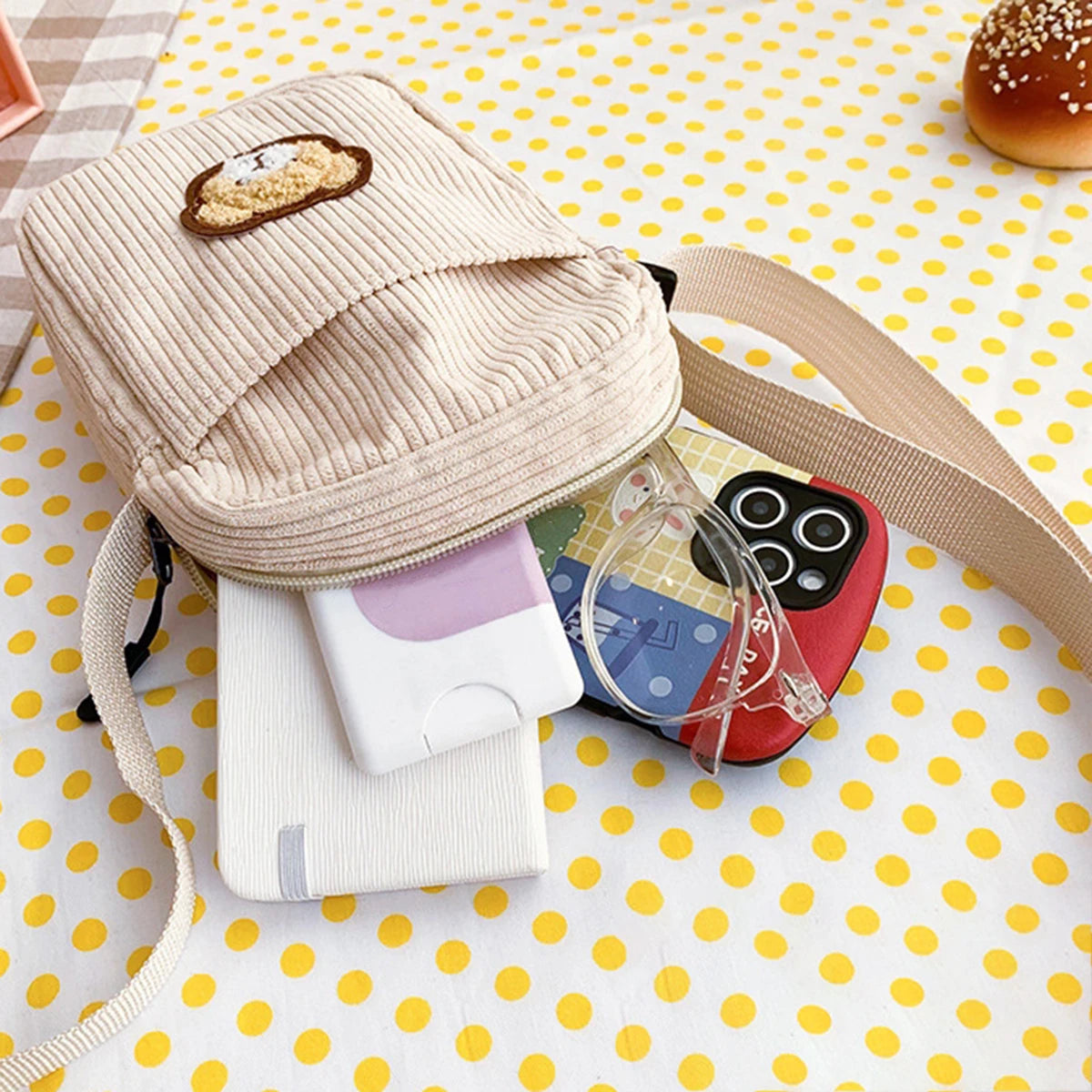 Small beige corduroy bag with a Kawaii cartoon design on a yellow polka dot surface.
