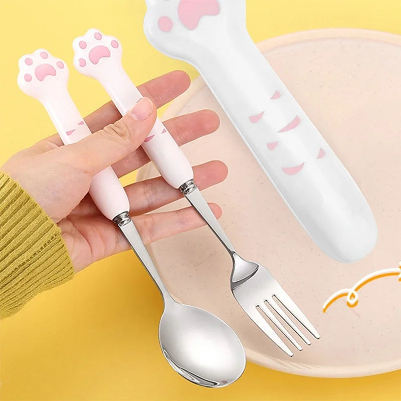 Kawaii utensils set with paw-shaped handles held by a hand on a yellow background