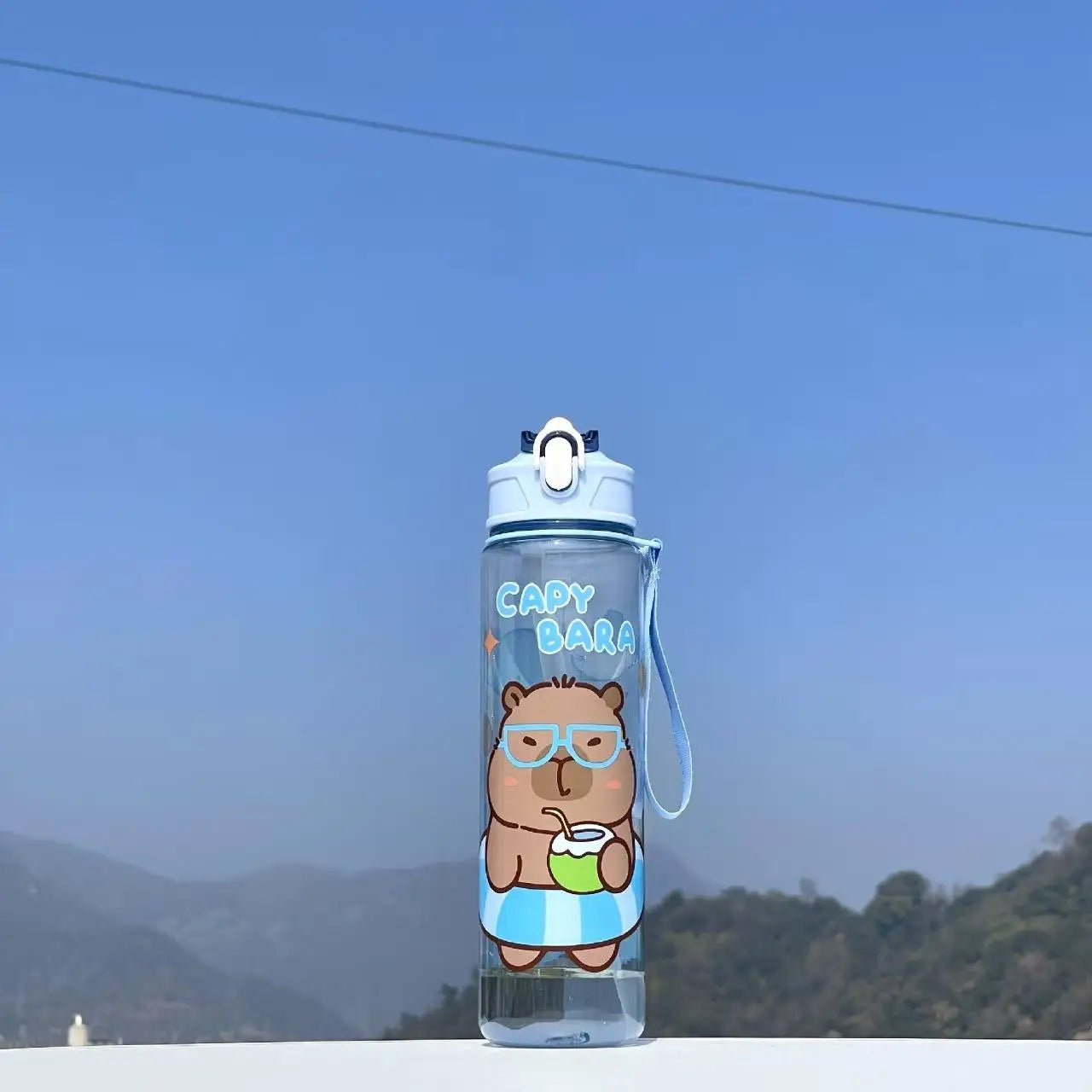 Capybara bear kawaii water bottle with 'Capybara' text against a blue sky