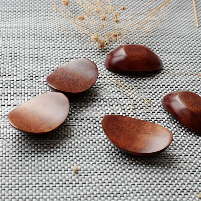 Wooden kawaii chopstick holders on a textured surface with dried plants.
