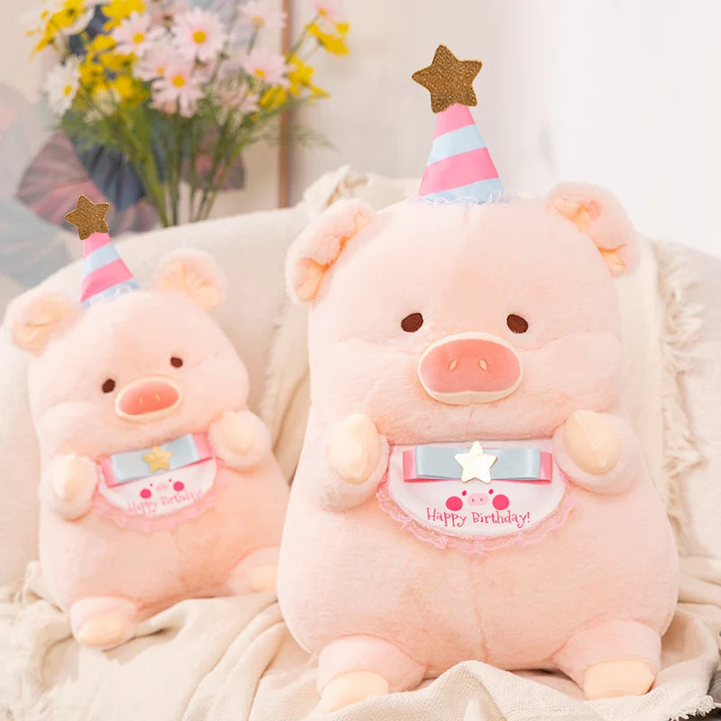 Two pink kawaii plush pigs with birthday hats on a soft surface with flowers in the background
