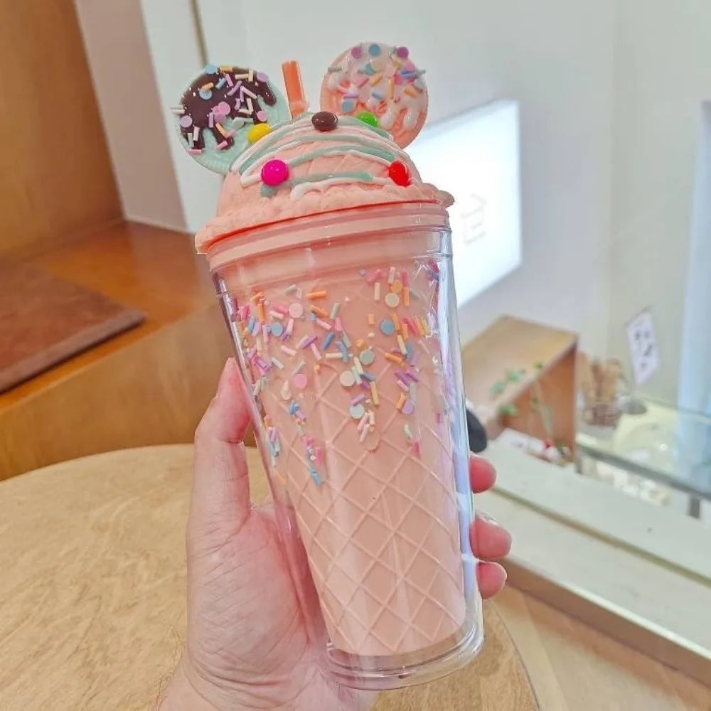 Pink ice cream-themed kawaii tumbler with decorative elements held by a hand indoors.