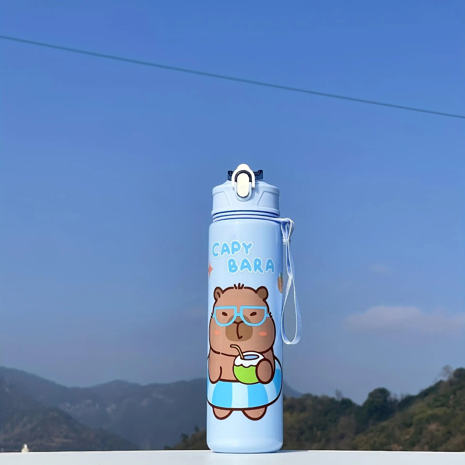 Blue kawaii water bottle with cartoon bear design against a blue sky