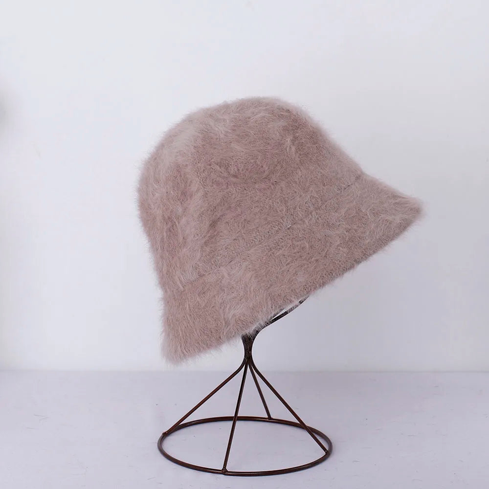 Fluffy beige bucket Kawaii hat on a black stand against a white background