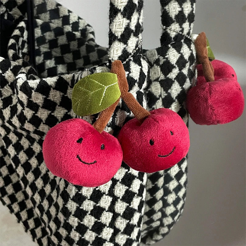 Plush kawaii apples with smiling faces attached to a checkered fabric bag.