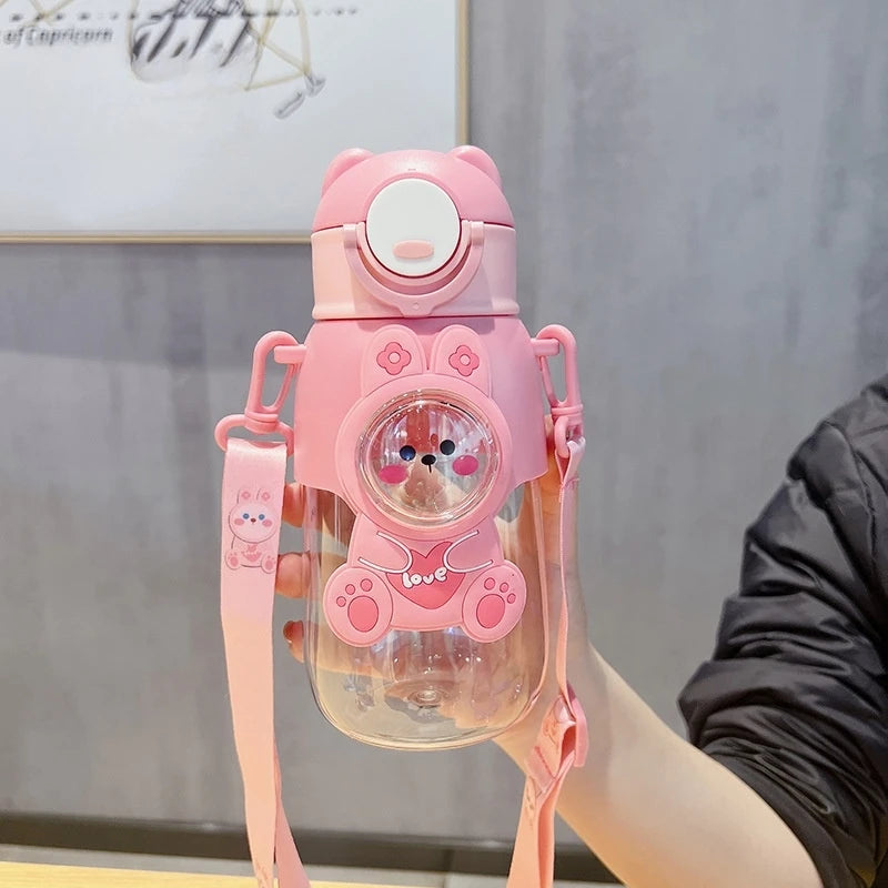 Pink cartoon kawaii water bottle with a strap held by a person against a neutral background