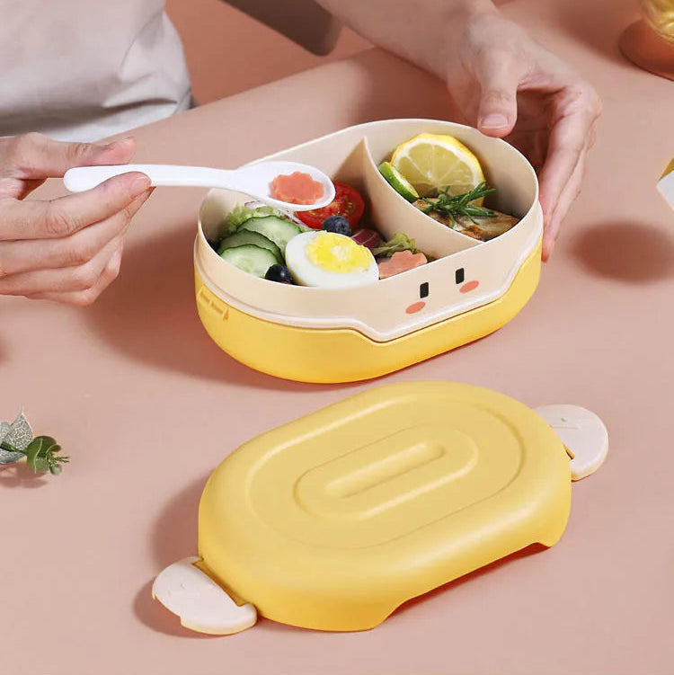 Yellow kawaii bento box with compartments filled with food on a pink surface.