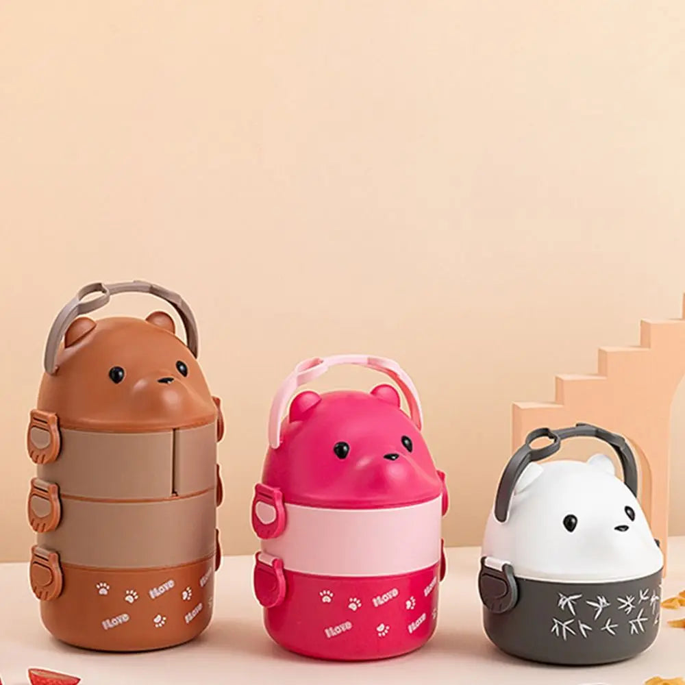 Three cartoon-style kawaii lunch containers in brown, pink, and white on a beige background