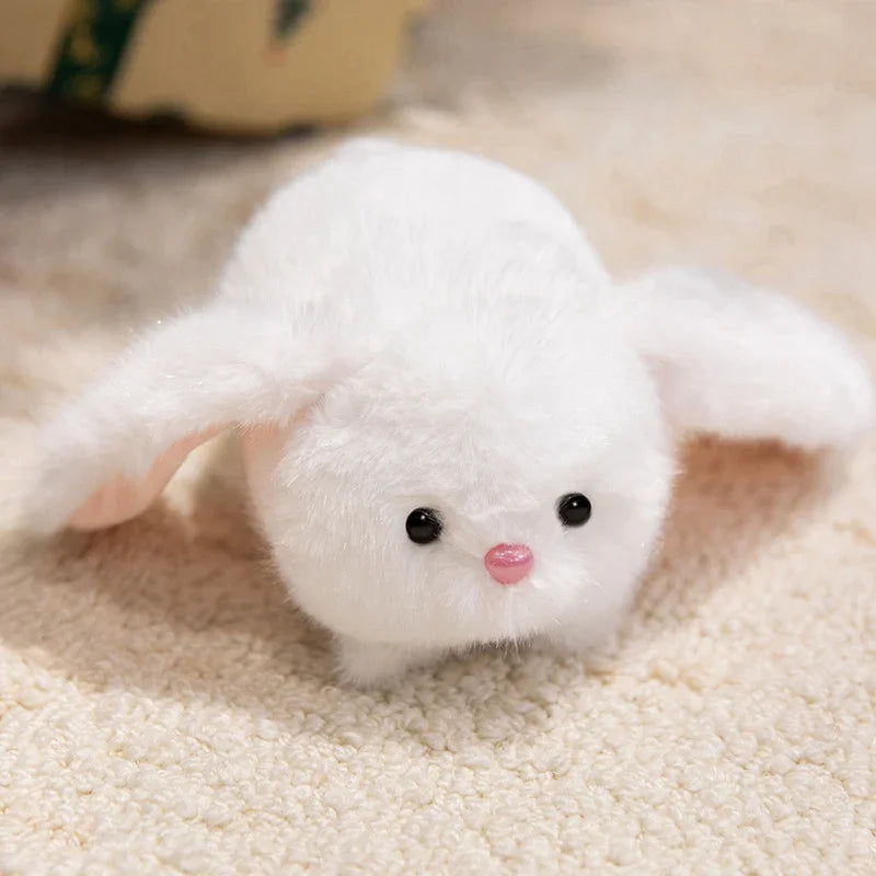 Small white kawaii plush toy with black eyes and a pink nose on a beige surface