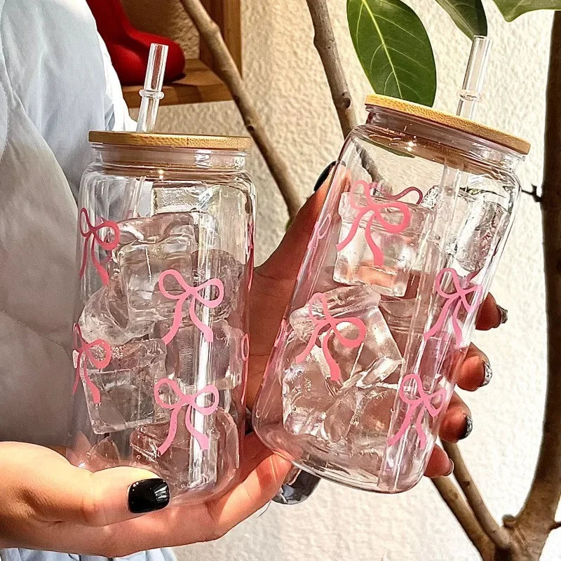 Two clear kawaii glass jars with wooden lids and pink bows held by a person.
