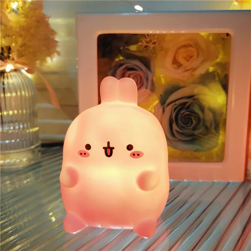 Cute pink kawaii cartoon-style lamp on a reflective surface with a floral arrangement in the background.