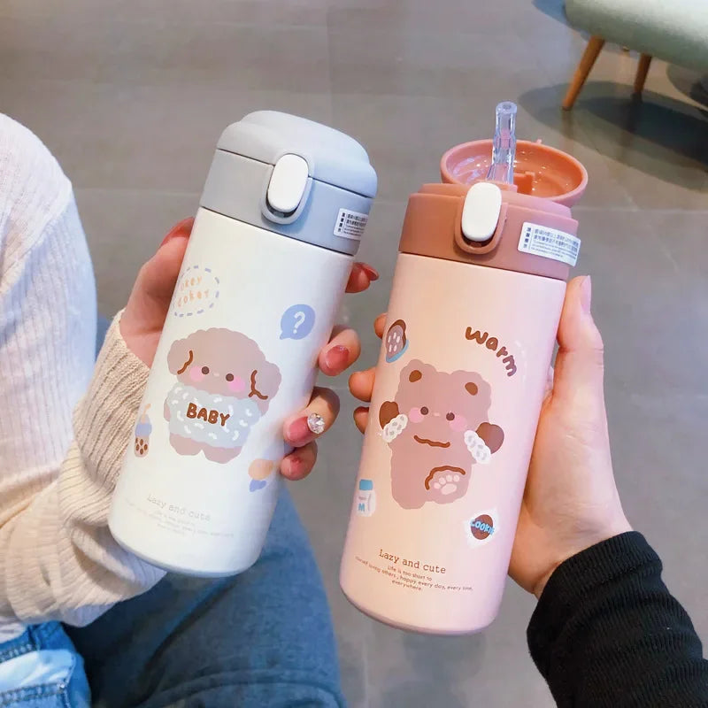 Two hands holding cute kawaii water bottles with cartoon designs on a neutral background.
