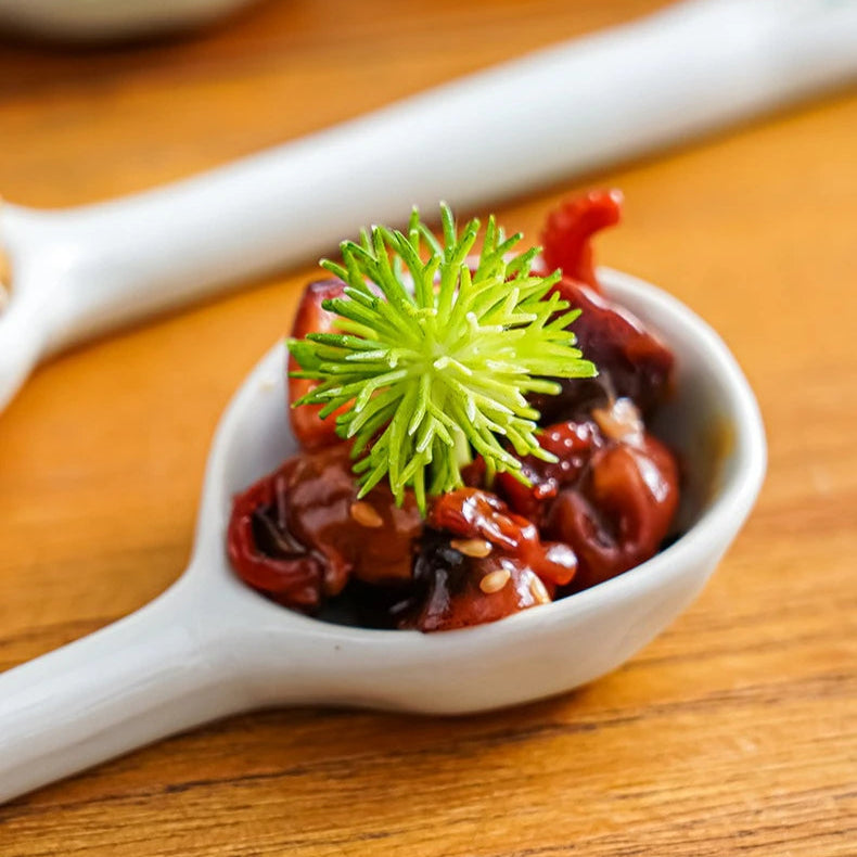 White kawaii spoon with a green spider web decoration on a wooden surface
