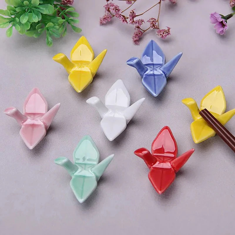 Colorful origami-style kawaii chopstick holders on a light surface with floral decorations.