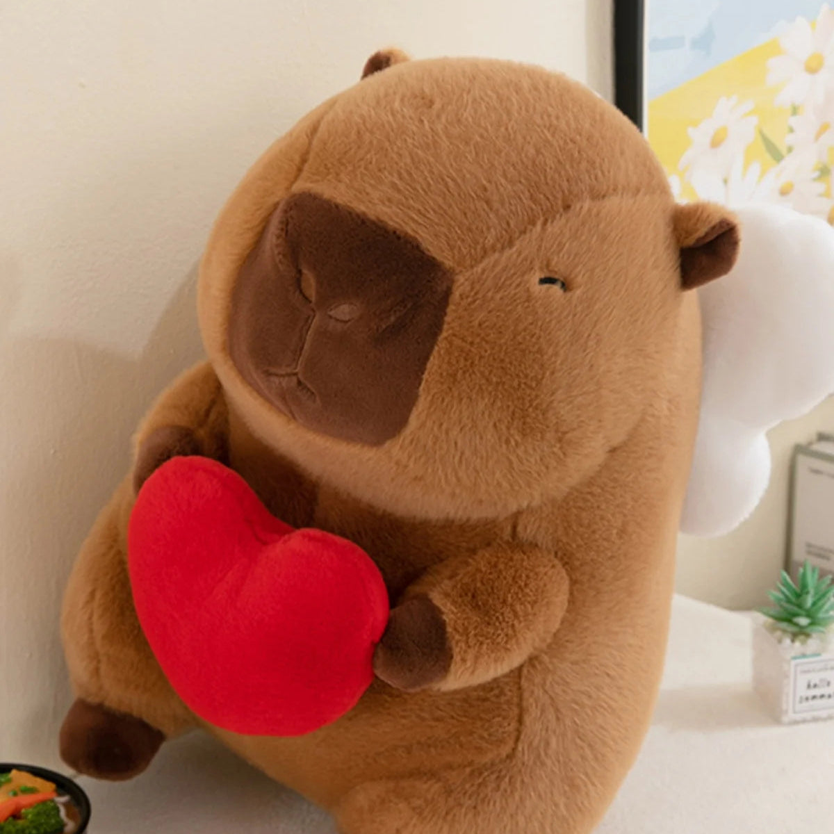 Kawaii plush animal toy holding a red heart on a light surface.