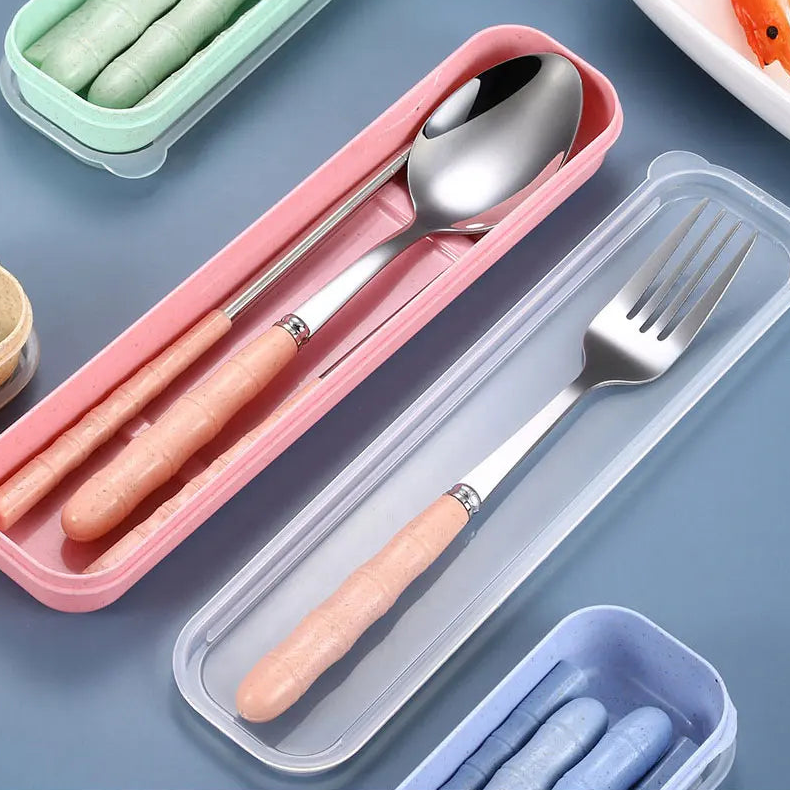 Set of silver kawaii utensils with pink handles in a transparent case on a blue surface.