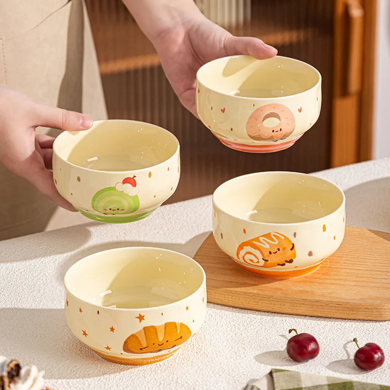 Set of four small ceramic kawaii bowls with animal illustrations on a wooden board.