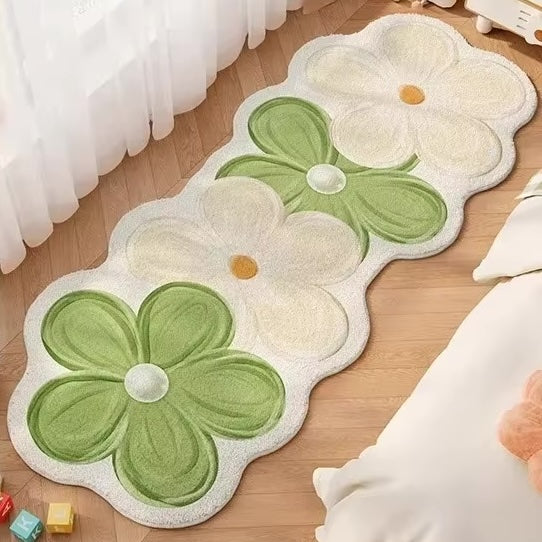 A rug with four flowers in green and cream on a wooden floor.