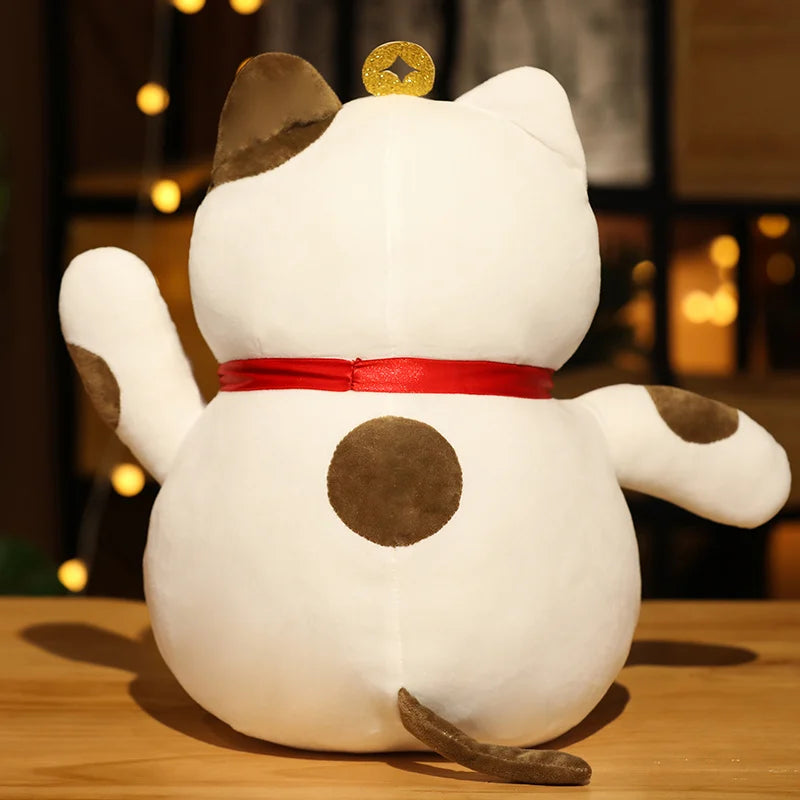 Kawaii plush toy shaped like a cat with a red ribbon on a wooden surface with a blurred background